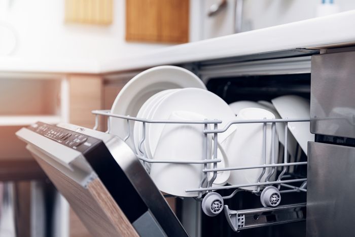 A dishwasher with the top rack open and clean dishes inside.